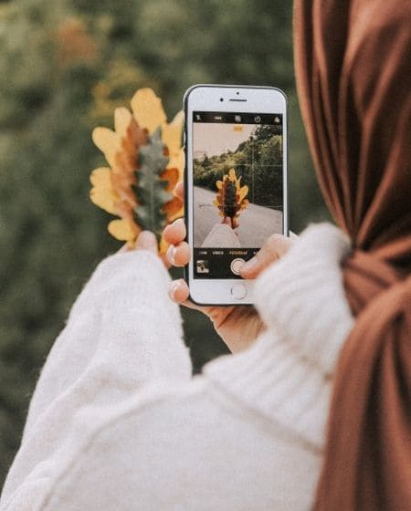 A girl taking pictures of fallen autumn leaves